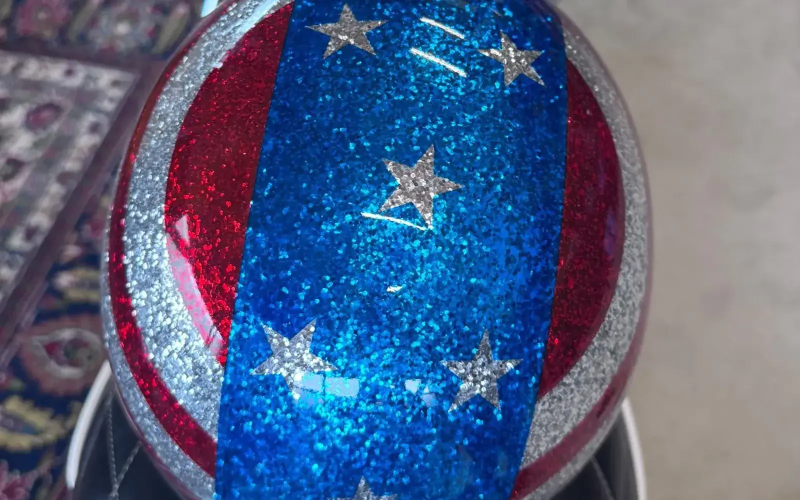 Helm mit Glitzer-Lackierung im Stars-and-Stripes-Design auf der Sitzbank einer Harley-Davidson